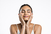 Portrait of young woman with eyes closed doing face massage
