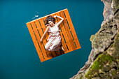 Luftaufnahme einer Frau, die auf einem Holzfloß liegt
