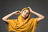 Studio-Porträt der schönen Frau mit goldenem Kopftuch