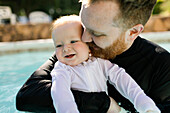 Vater umarmt seinen kleinen Sohn (12-17 Monate) im Schwimmbad