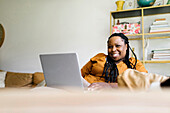Smiling woman sitting on sofa and working on laptop