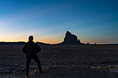 USA, New Mexico, Silhouette eines Mannes mit Blick auf Ship Rock bei Sonnenuntergang