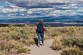 USA, New Mexico, Los Alamos, Rückansicht einer Frau beim Wandern im Tsankawi-Abschnitt des Bandelier National Monument