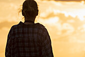 Rear view of woman standing against sunset sky