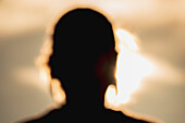 Unscharfe Silhouette eines Frauenkopfes bei Sonnenuntergang