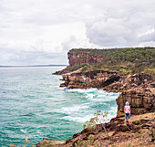 Australien, New South Wales, Port Macquarie, Frau steht auf einer Klippe und blickt auf die Aussicht