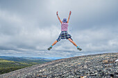 Australien, New South Wales, Bald Rock National Park, Frau springt im Freien mit den Händen in die Luft