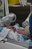 Ärzte mit weinendem neugeborenem Mädchen (0-1 Monate) im Krankenhaus