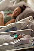 Mother lying with newborn baby girl (0-1 months) in hospital
