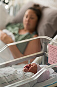 Liegende Mutter mit neugeborenem Mädchen (0-1 Monate) im Krankenhaus