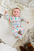 Baby girl (0-1 months) in pajamas lying on bed