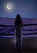 Dubai, United Arab Emirates, Woman in luxury resort in desert watching moon and starry sky at night