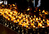 China, Tibet, Lhasa, Brennende Kerzen in einem tibetischen buddhistischen Tempel