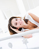 Porträt einer lächelnden jungen Frau auf dem Bett liegend