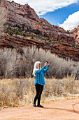 USA, Utah, Escalante, Woman taking pictures while hiking in Grand Staircase-Escalante National Monument