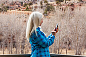 USA, Utah, Escalante, Frau benutzt Smartphone im Grand Staircase-Escalante National Monument