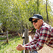 Älterer Landwirt lehnt an einem Holzzaun in der Nähe von Sun Valley