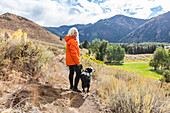 USA, Idaho, Sun Valley, Lächelnde Frau mit Border-Collie-Hund in der Landschaft nahe Bald Mountain