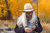 USA, Idaho, Bellevue, Senior woman putting bait on fishing rod