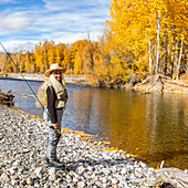 USA, Idaho, Bellevue, Portrait of senior woman fly-fishing in Big Wood River in autumn