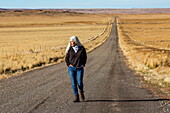USA, Nevada, Winnemucca, Ältere Frau geht Wüstenstraße hinunter