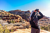 United States, Utah, Escalante, Senior hiker looking through binoculars