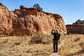United States, Utah, Escalante, Senior hiker photographing rock formations