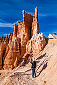 United States, Utah, Bryce Canyon National Park, Senior hiker photographing rock formations