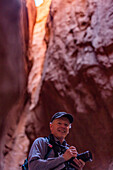 United States, Utah, Escalante, Senior male hiker with camera in canyon