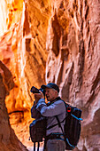 Vereinigte Staaten, Utah, Escalante, Älterer Wanderer beim Erkunden und Fotografieren von Felsformationen im Kodachrome Basin State Park in der Nähe des Escalante Grand Staircase National Monument