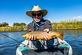 Senior fly fisherman holds brown trout before releasing back into spring creek