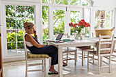 Mature woman with laptop in dining room