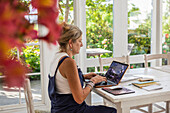 Mature woman with laptop in dining room