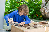 Boy (8-9) cutting a cardboard box