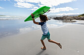 Südafrika, Hermanus, Junge (8-9) mit Surfbrett am Strand