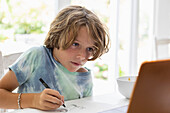 Junge (8-9) malt ein Bild während des Online-Unterrichts