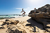 Südafrika, Westkap, Mädchen (16-17) springt von einem Felsen am Strand im Lekkerwater-Naturreservat