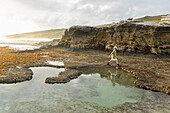 South Africa, Western Cape, Boy (8-9) exploring tidal pools in Lekkerwater Nature Reserve