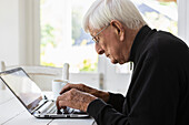 Älterer Mann arbeitet zu Hause an seinem Laptop