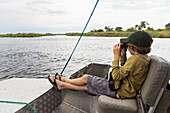 Africa, Zambia, Boy (8-9) in boat on Zambezi River near Tongabezi River Lodge