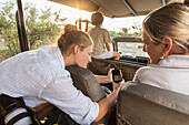 Africa, Namibia, Woman with son (8-9) and daughter (16-17) in safari vehicle
