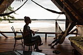 Afrika, Sambia, Livingstone, Bruder (8-9) und Schwester (16-17) entspannen in Lodge am Sambesi-Fluss