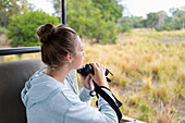Afrika, Sambia, Mädchen (16-17) im Safarifahrzeug mit Fernglas