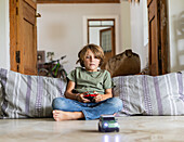Boy (8-9) playing with remote-control toy car at home