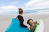 Girl (16-17) and boy (8-9) with body boards on Grotto Beach