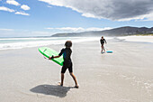 South Africa, Hermanus, Girl (16-17) and boy (8-9) with body boards on Grotto Beach