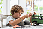 Junge (8-9) baut Auto-Modellspielzeug