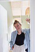 Porträt eines Mädchens im Teenageralter (16-17), das in der Tür steht und lächelt