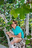 Junge (10-11) klettert im Sommer auf einen Baum