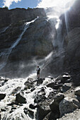 Russland, Karatschai-Tscherkessien, Arkhyz, Mann steht in der Nähe des Sofiyskiye Vodopady Wasserfalls im Kaukasusgebirge